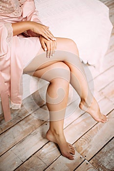 Beautiful tanned slim legs of young woman wearing pink dressing gown