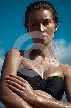 Beautiful tanned woman on the beach and sunbathing. Glitters on her perfect slim body.
