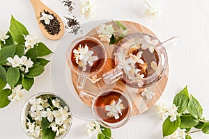 Beautiful tea composition with a modern teapot and cups with tea fragrant jasmine. top view. white textured background