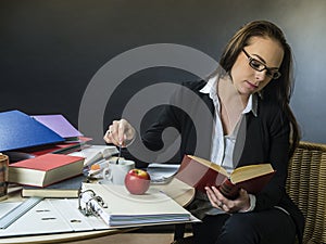 Beautiful teacher sitting at her desk reading