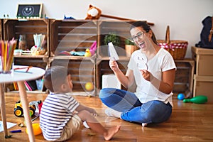 Beautiful teacher teaching alphabet to student toddler boy at kindergarten