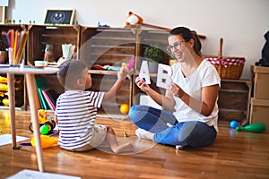 Beautiful teacher teaching alphabet to student toddler boy at kindergarten