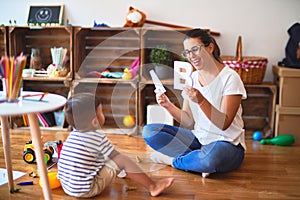 Beautiful teacher teaching alphabet to student toddler boy at kindergarten