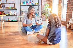 Beautiful teacher teaching alphabet to student toddler girl at kindergarten