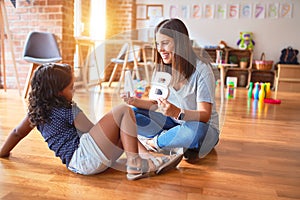 Beautiful teacher teaching alphabet to student toddler girl at kindergarten