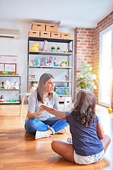 Beautiful teacher teaching alphabet to student toddler girl at kindergarten