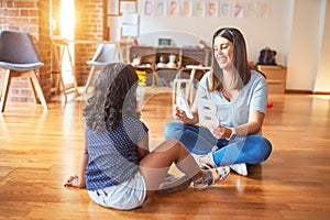 Beautiful teacher teaching alphabet to student toddler girl at kindergarten