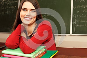 Beautiful teen achiever in classroom near desk happy smiling