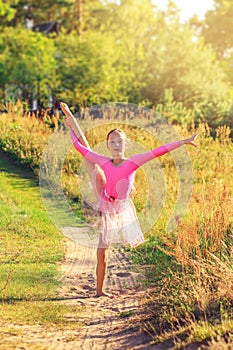 Beautiful teen girl  Is dancing outside at  the field at summer sunset