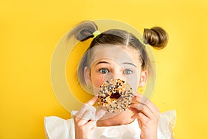 Beautiful teen girl eating a donut. emotionally laughing. on a yellow yak background. summer sunny picture