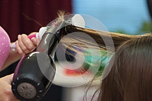 Beautiful teen girl at the hairdresser blow drying her short hair