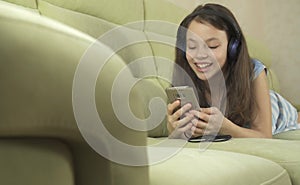 Beautiful teen girl in headphones singing karaoke songs in smartphone