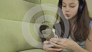 Beautiful teen girl in headphones singing karaoke songs in smartphone with dog stock footage video