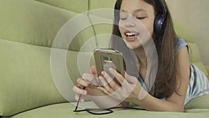 Beautiful teen girl in headphones singing karaoke songs in smartphone stock footage video