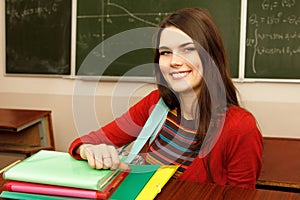 Beautiful teen girl high achiever in classroom near desk happy s