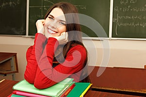 Beautiful teen girl high achiever in classroom over desk happy s