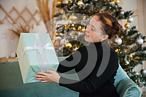 Beautiful teen girl   near   Christmas tree with gift