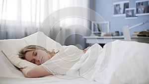 Beautiful teen girl peacefully sleeping in bad, relaxing in morning, rest time