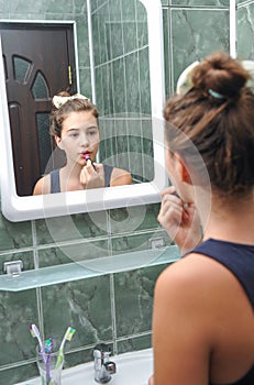 A beautiful teen girl putting lipstick and checking if she looks fine