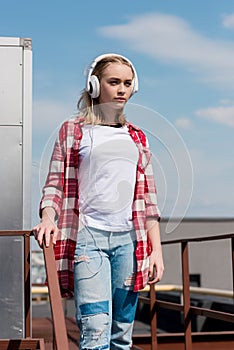 beautiful teen girl in red plaid shirt and headphones in front of