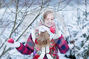 Beautiful teen girl in Russian national clothes with red apples in winter hands