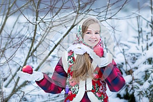 Beautiful teen girl in Russian national clothes with red apples in winter hands