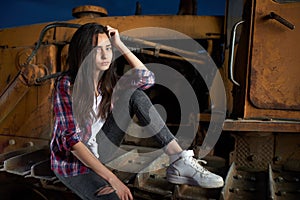 Beautiful teen girl sitting on an old tractor