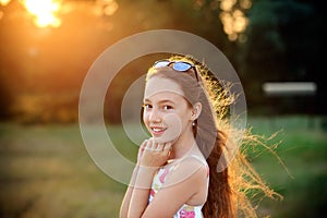 Beautiful Teen Girl is smiling and  enjoying nature in the park at Summer sunset