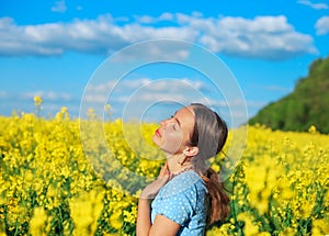 Beautiful teen girl is smiling with yellow flowers in summer field