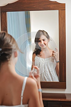 A beautiful teen girl studies her appearance as she looks into the mirror photo