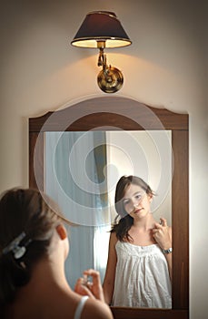 A beautiful teen girl studies her appearance as she looks into the mirror photo