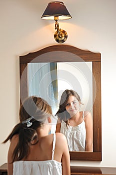 A beautiful teen girl studies her appearance as she looks into the mirror