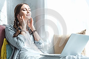 beautiful teen girl using laptop and listening music with earphones