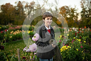 Beautiful teenage girl in blossoming dahlia field. Child picking fresh flowers in dahlia meadow on sunny autumn day