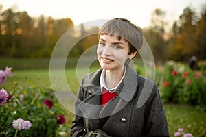 Beautiful teenage girl in blossoming dahlia field. Child picking fresh flowers in dahlia meadow on sunny autumn day