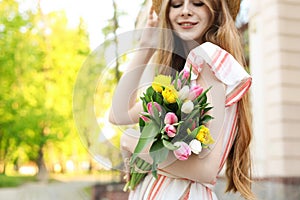 Beautiful teenage girl with bouquet of tulips outdoors, focus on flowers. Space for text