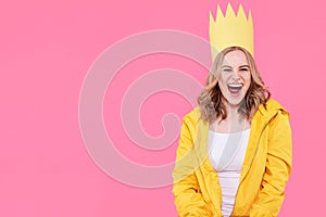 Beautiful teenage girl in bright yellow jacket and party hat shouting with excitement. Attractive cool woman fashion portrait.