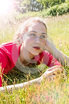 Beautiful teenage girl dreaming, relaxing in the grass for wellbeing