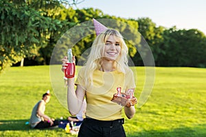 Beautiful teenage girl in a festiv hat on her birthday with a cake and candles.