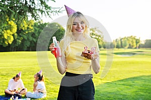 Beautiful teenage girl in a festiv hat on her birthday with a cake and candles.