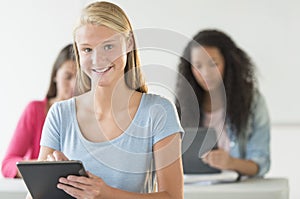 Beautiful Teenage Girl Holding Digital Tablet In Classroom