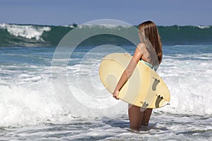 Beautiful Teenage Girl Holding a Surfboard at the Beach Smiling