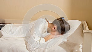 Beautiful teenage girl jumping on bed and crying in pillow. Teenager depression and social problems