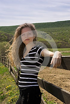 Beautiful teenage girl leaning on a fence