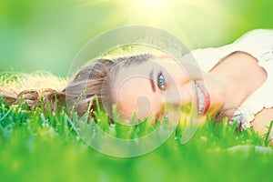 Beautiful teenage girl lying on green grass