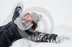 Beautiful teenage girl lying in the snow