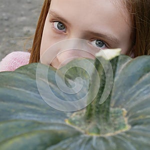 Beautiful teenage Girl near Big Green Pumpkin, close-up