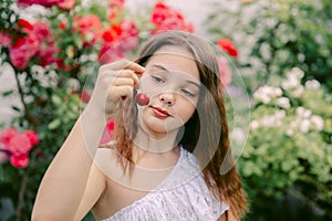 Beautiful teenage girl picking cherries, looks at her