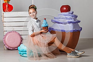 Beautiful teenage girl in pink tutu skirts with lollipops and macaroons and fansy cakes in studio on white background