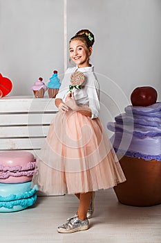 Beautiful teenage girl in pink tutu skirts with lollipops and macaroons and fansy cakes in studio on white background